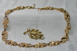 lot 222 image: Gold plated foliage link with crystals. Fold over clasp. Missing 1 small crystal. 14L Includes a gold finish faux seed pearl broochpin. 1.5L
