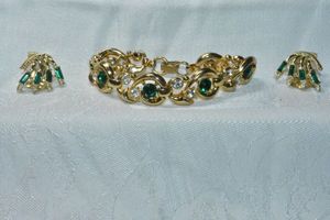 lot 235 image: Signed Bogoff (1940 - 1960s) Emerald and clear rhinestone clip earrings 1W and gold finish clear AB and green rhinestone bracelet. 7.5L Fold over clasp. Earrings marked Bogoff