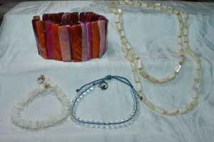 lot 268 image: Shell jewelry selection. Includes signed 4Oceans recycled glass bead bracelet in branded pouch, Puka shell bracelet 7L, shell bar stretch bracelet, and 36L continuous shell tub bead necklace.