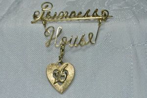 lot 276 image: Princess House script dangle broochpin with heart shaped 16 charm. 2W x 2.25H