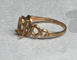 lot 322 image: 10K yellow gold ring mount. Size 4. Marked 10K inside. One gemstone prong is missing.