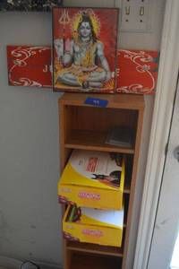 lot 99 image: Narrow bookshelf and contents 2 boxes of Ivermectin for horses, Buddha wall hanging and Just Kiss Me wall hanging