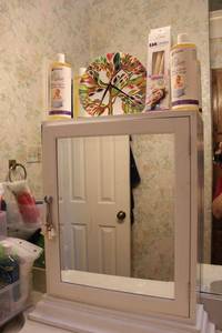 lot 35 image: Antique Countertop Medicine cabinet with Russian glass art clock, Baby shampoo and ear wax candles. Open lot to click on link provided for more information.