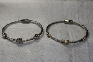 lot 26 image: (2) Twisted wire metal bangle bracelets with gold plated accents and diamond simulants. Magnetic closures.
