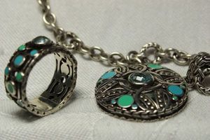 lot 39 image: Signed John Hardy Designs demi parure set. Includes enamel decorated disc pendant necklace 18L and band ring Size 8. Both marked 925 JHD