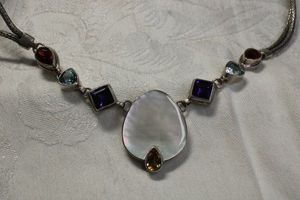 lot 49 image: Sterling Silver and gemstone necklace with herringbone braided yoke. Includes MOP, Amethyst, Blue Topaz and Garnet. Toggle clasp. Marked 925. 16L