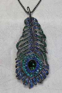 lot 138 image: Signed Kenneth Jay Lane crystal decorated peacock feather pendant on burnished 28L necklace. Marked KJL and has KJL hang tag. Pendant 3.5L