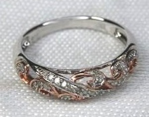 lot 142 image: Sterling Silver and diamond ring with bi-color scrollwork. Diamonds tested. Marked 925. Size 7.5