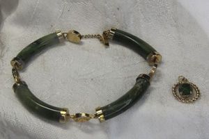 lot 249 image: Nephrite Spinach Jade curved panel bracelet with gold finish hardware, hidden box clasp and safety catch. No markings. Also includes a Jade pendant.