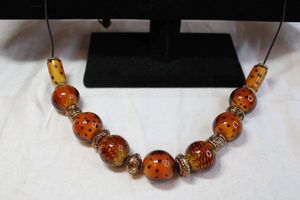 lot 51 image: Oversized burnt orange spotted glass bead Autumnal necklace on adjustable 28L cord with bronze color separators. Beads have white glass centers. Beads are larger than shooting marble size - about 21mm.