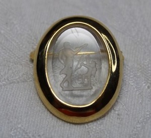 lot 53 image: Vintage Victorian Revival oval gold plated broochpin with prong set intaglio glass depicting male soldier holding Cupids arrow and Cupid attempting to reach for same. 1.25L