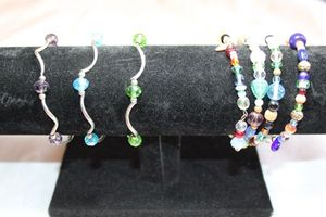 lot 81 image: Multi color glass and mixed material tension spiral wrapround bracelet. Also includes (3) silver finish stretch bracelets with blue, green and purple station beads.