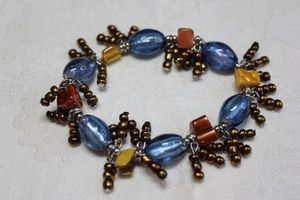 lot 84 image: Blue glass bead, shell bead and copper colored bead stretch dangle movement bracelet.