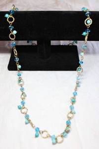 lot 88 image: Faceted blue glass bead with acrylic blue round beads on a gold finish textured circle link necklace. 32L Lobster clasp.
