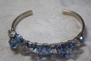 lot 90 image: Faceted blue and clear wire wrapped decorated cuff silver finish bracelet. Bracelet marked Sterling.