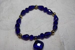 lot 106 image: Midnight blue glass stretch bracelet with large blue dangle charm.
