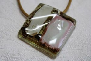 lot 159 image: Dichroic glass cream, brown and pink square pendant on 14L woven golden silk necklace. Lobster clasp. Pendant 2W