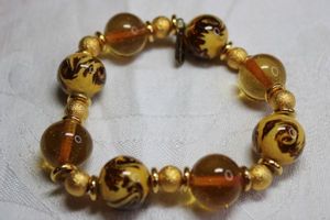 lot 165 image: Signed Hilary London ( Hilary Foster, New York, 1986 - 2007 approx , known for Murano jewelry ) Murano Glass gold  lampwork bead stretch bracelet. Has hang tag. Matches necklace in Lot 164