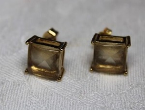 lot 112 image: Prong set faceted pale yellow glass poststud earrings. 11x9mm approx. Could use good cleaning.