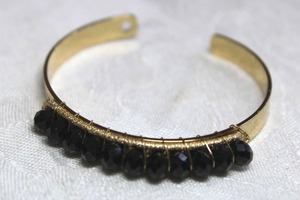 lot 116 image: Gold finish cuff bracelet with faceted black glass crystals and a heart shaped cutout on cuff.