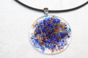 lot 123 image: Artisan crafted glass disc pendant with textured blue and gold crystals (likely beach glass crystals) on a silkie rubber 14L necklace. Marked Silkie on pull clasp.