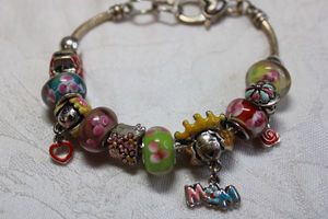 lot 135 image: Charm bracelet with glass beads, glass lampwork beads and I Love Mom enamel specialty beads. Heart shape clasp. 8L