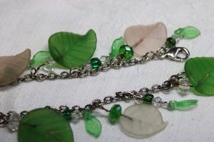 lot 195 image: Silver finish bracelet with translucent white and green satin glass dangles in leaf form. Lobster clasp. 7.5L