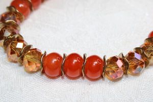 lot 196 image: Faceted orange and orange rondel bead glass stretch bracelet with gold finish separators.