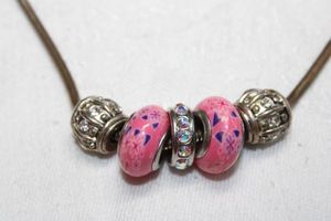 lot 212 image: Flexible snake chain necklace with pink art glass and rhinestone decorated slide beads. 22L with spring ring clasp.