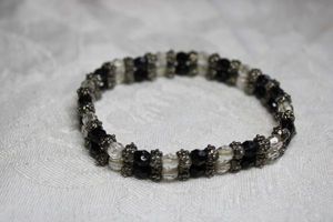 lot 214 image: Black and clear faceted glass bead stretch bracelet with metal flower separators. Double row.
