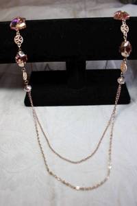 lot 222 image: Rose gold color necklace with large rose pink hue glass trillion cut stations. Quality piece. 34L with 3 extender.