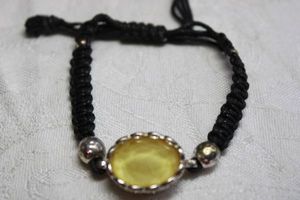 lot 227 image: Woven pull tight bracelet with faceted oval lemon glass focal piece with silver mount.