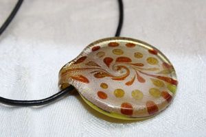 lot 236 image: Dichroic glass cream, brown and gold round pendant on 24L leather corded necklace. Lobster clasp. Pendant 1.5W