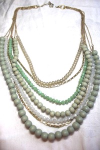 lot 240 image: Muted green hue multi strand necklace with wood, satin glass and faceted glass beads with gold finish yokes and chains. 18L with lobster clasp and 3 extender.