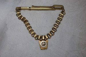 lot 20 image: 10K yellow gold and enamel Rotary insignia on a chained tie bar. Insignia marked 10K