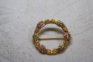 lot 15 image: 12K Black Hills Gold style tri colored leaf wreath brooch. Marked 12K on reverse. 1W