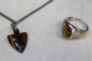 lot 35 image: Sterling Silver ring with Tiger Eye cabochon. Marked 925. Includes a Tiger Eye arrow head pendant Avon necklace.