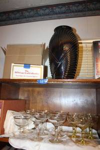 lot 62 image: Purple carnival glass vase, 1876 Cape Cod red glasses (in original box), Champagne glasses - one set is yellow glass with etched design, one is gold rimmed set, plus cloth napkins (some in original box)