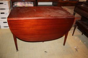 lot 85 image: Vintage Dual drop leaf dining table -  Ribbon Mahogany wood, 4 leaves. Measures 24x42 and 5ft x 42 with dual sides extended, each leaf measures 12x42, Has original tag from Extensole Sparta, MI. Matching chairs in lot 291.