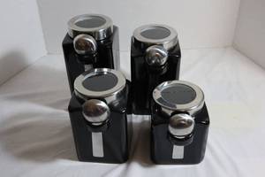 lot 77 image: Set of 4 Black Kitchen Canisters.  Each one comes with its own measuring spoon.  Gently Used - One lid is cracked.