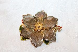 lot 299 image: Signed Kenneth Cole poinsettia broochpin with mesh leaves and enamel leaves and berries. Marked KC on reverse. 2W