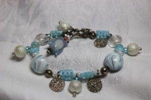 lot 290 image: Glass bead stretch bracelet adorned with metal snow flakes and snowballs and glass millefiori style cuboid beads. Has glass penguin charm