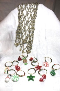 lot 266 image: Holiday party wine glass markers with glass charms. (12 count). Includes a metal beaded mesh wine bottle cover decoration.
