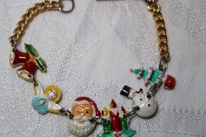 lot 263 image: Vintage holiday themed bracelet with incorporated painted stamped aluminum metal charms. Fold over clasp. 7L
