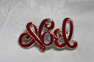 lot 244 image: Figural script Noel broochpin in red enamel. 1.50W