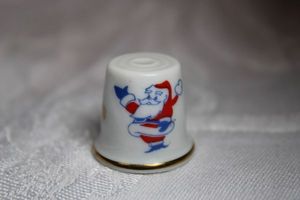 lot 232 image: Santas Workshop (North pole, Colorado) thimble with vintage Santa image. White ceramic with gold trim.