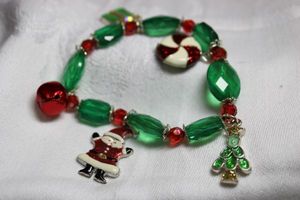 lot 228 image: Green and red acrylic bead stretch bracelet with enamel charms (gift, candy, elf and tree, bell).