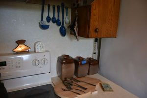 lot 75 image: Brown ceramic canister set, Silver plate silverware, pig cutting board blue speckled metal spoons. Plus Alaska souvenir knife