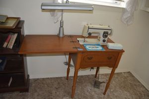 lot 99 image: Vintage New Home sewing machine model 443S with table. Includes lamp clamped to table.