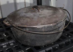 lot 23 image: Pre Seasoned Very Little use Cast Iron pouring Dutch Oven with Lid and hanging handle
